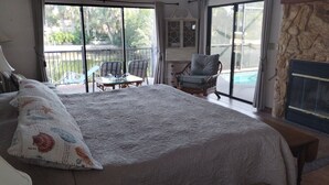 A bedroom with a large bed, a balcony with a table and chairs, and a view of a swimming pool. - Waterfront home on deep water canal (Hernando Beach)