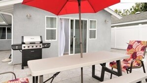 A patio with a table and chairs, a grill, and a red umbrella. - New Carlsbad Beach house - Blocks from beach with rare  cental Air Conditioning (Carlsbad)