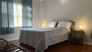 A bedroom with a bed, two bedside lamps, a window with curtains, and a wooden floor. - Discover Oxford Charm, Just A Quick 5-min Drive To University of Mississippi
 (Oxford)