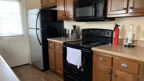 A kitchen with wooden cabinets, a black refrigerator, a microwave, a stove, and a sink. - Discover Oxford Charm, Just A Quick 5-min Drive To University of Mississippi
 (Oxford)
