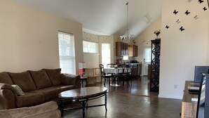A spacious living room with a brown sofa, a round coffee table, and a dining area with a white tablecloth. - Discover Oxford Charm, Just A Quick 5-min Drive To University of Mississippi
 (Oxford)