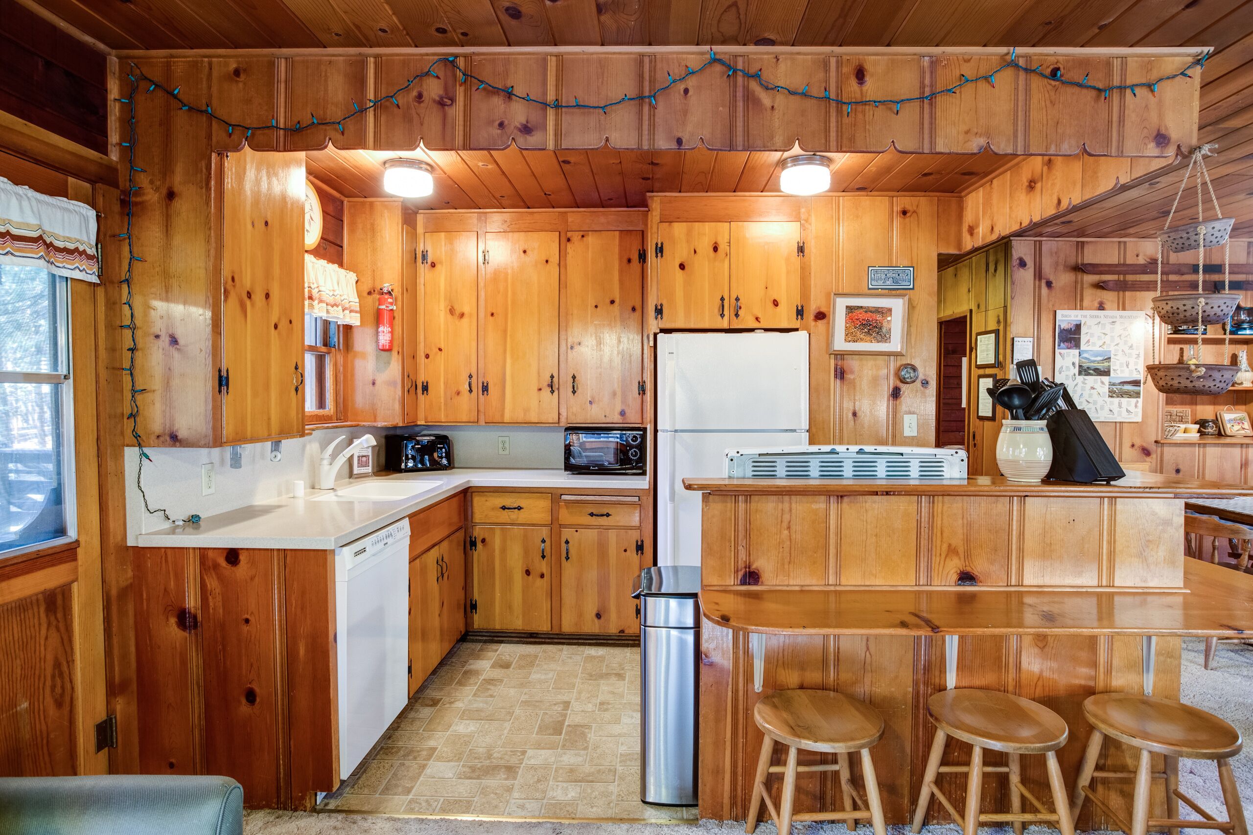 Cucina in legno con isola centrale, sgabelli da bar, lavastoviglie, frigorifero e microonde.