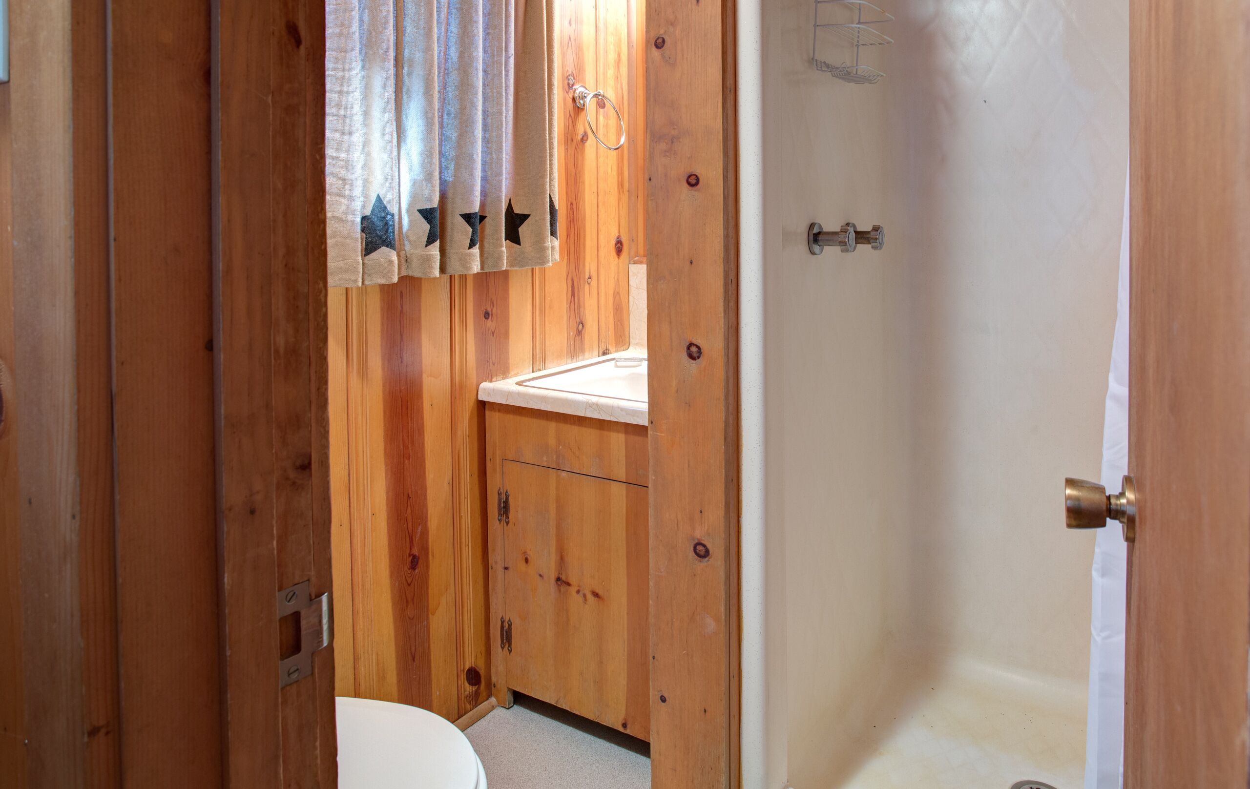 Un baño de madera con inodoro, lavamanos y ducha.