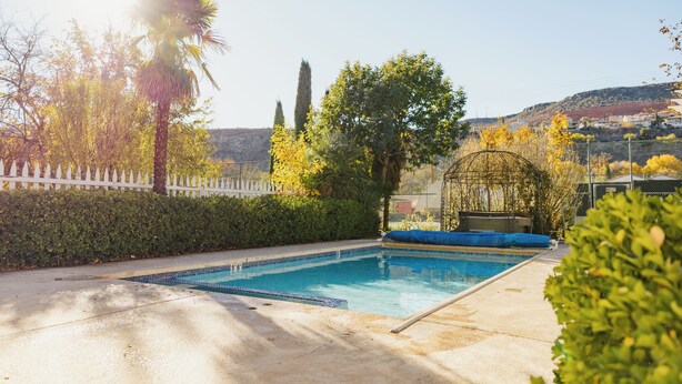 A swimming pool with a white fence, trees, and a clear sky. - Perfect for Families (St George)