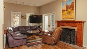 A living room with a sectional sofa, a recliner, a coffee table, a fireplace, and a painting on the wall. - Perfect for Families (St George)