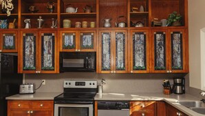 A kitchen with wooden cabinets, a microwave, a toaster, a stove, and a dishwasher. - Perfect for Families (St George)