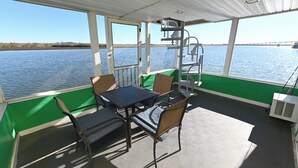 Un espace extérieur abrité, avec une table et des chaises, donnant sur une étendue d’eau.