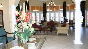 A spacious lobby with a large seating area, a decorative fountain, and a view of the outdoors through large windows. - Gorgeous South-Facing Pool/Spa/Lanai, No Rear Neighbor, Gated Resort Amenities (Davenport)