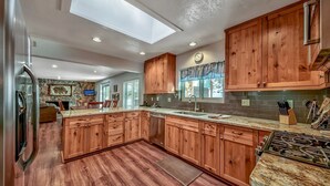 A spacious kitchen with wooden cabinets, a granite countertop, and a skylight.