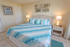 A bedroom with a bed, two bedside tables, a door, and wall art.
