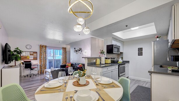 A modern apartment with a dining area set for four, a kitchen with a microwave and refrigerator, and a living area with a sofa and a coffee table. - Fantastic Strip view walking distance 2br2b condo (Las Vegas)