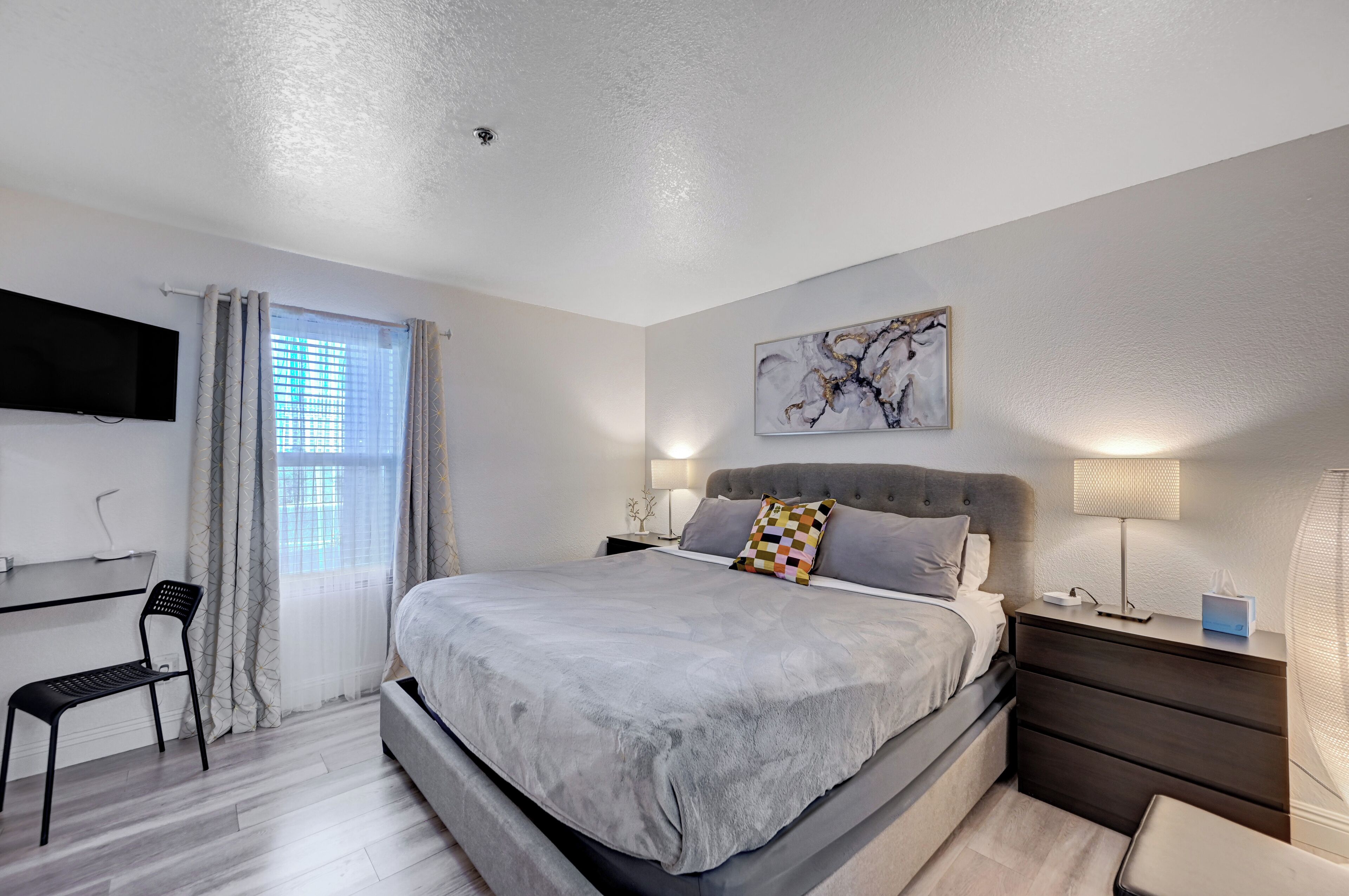 A modern bedroom with a large bed, a desk, and a chair.