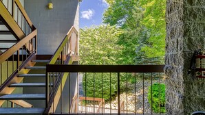 Eine Treppe mit Metallgeländern führt zu einem Balkon mit einer Steinmauer und einem Feuerlöscher.
