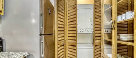 A compact kitchen with a refrigerator, oven, and wooden cabinets.