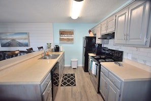A modern kitchen with a central island, stainless steel appliances, and light blue walls.