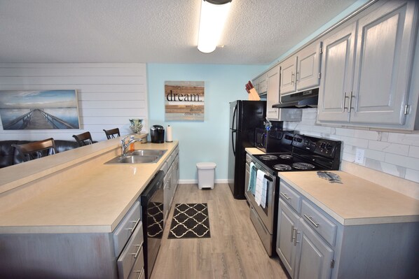 A modern kitchen with a central island, stainless steel appliances, and light blue walls.