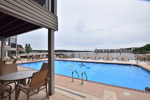 A pool area with lounge chairs and a view of the city.