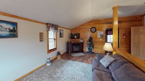A cozy living room with a fireplace, a television, a Christmas tree, and a couch. - Sandy Run Cabin-Hot Tub, Hocking Hills, WNF, more (Hocking Hills)