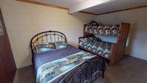 A bedroom with a single bed, a bunk bed, and a wooden headboard.