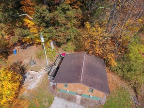 An aerial view of a building with a sloped roof, surrounded by autumn foliage.
