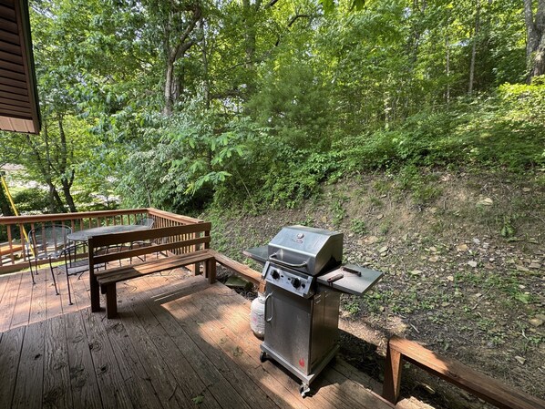 A deck with a grill, wooden bench, and metal chairs. - Sandy Run Cabin-Hot Tub, Hocking Hills, WNF, more (Hocking Hills)
