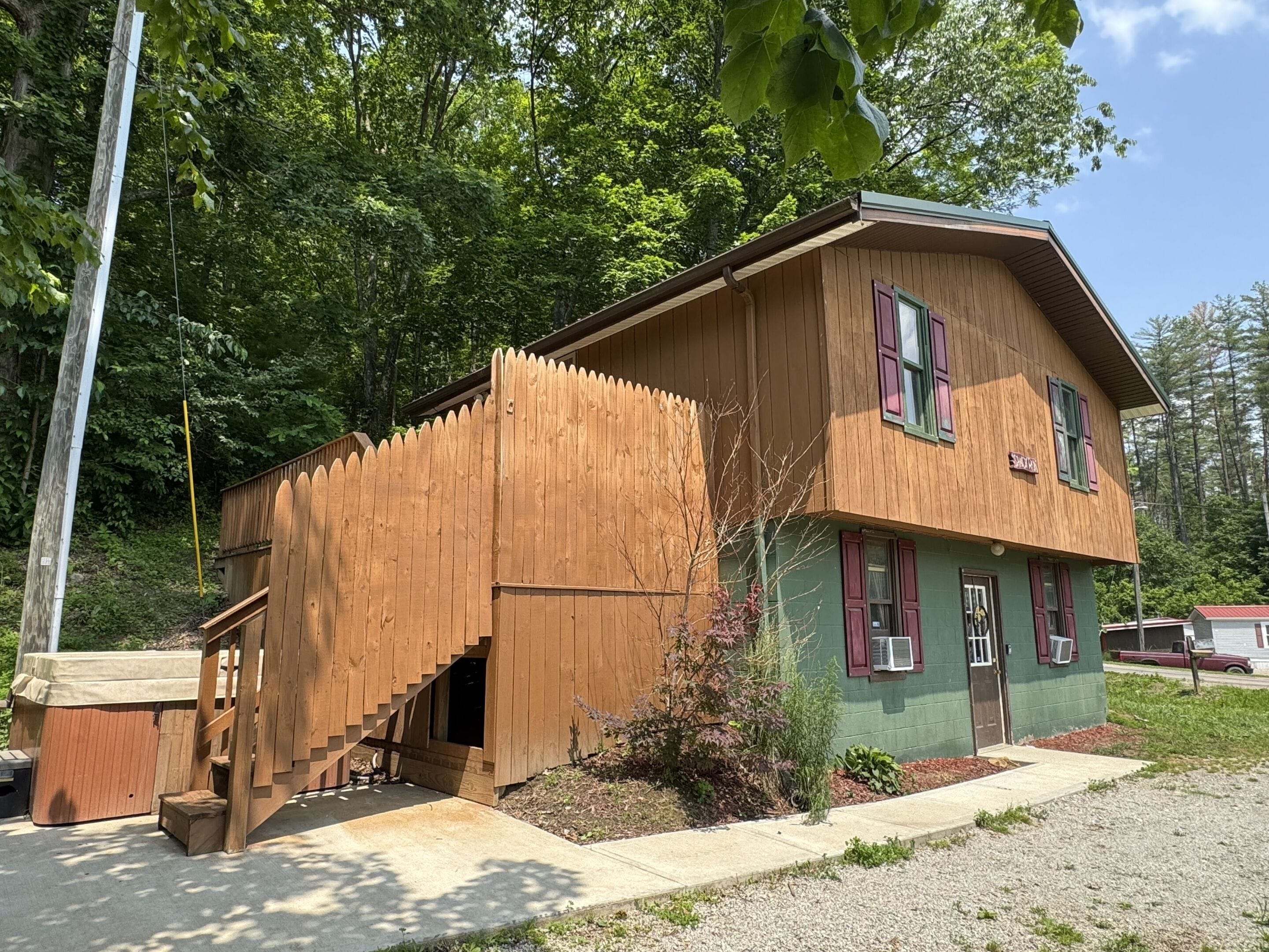 Une cabane en bois avec un escalier menant à une porte, entourée d’arbres.