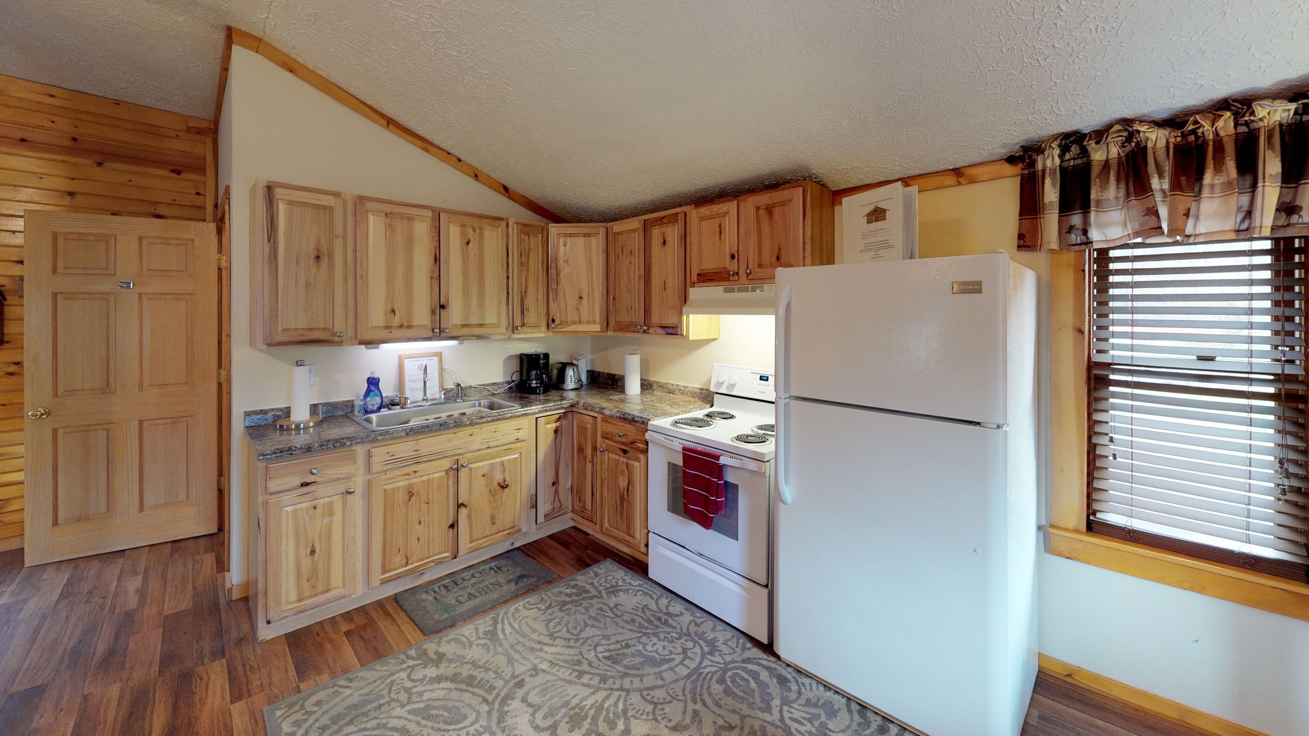 Une cuisine de taille réduite, avec des meubles de rangement en bois, un réfrigérateur blanc et une cuisinière.