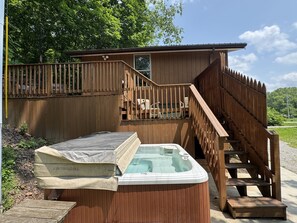 Eine Holzhütte mit Whirlpool und einer Treppe zu einer Terrasse.