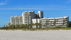 Ett hotell vid stranden med flera våningar, balkonger och en sandstrand framför.