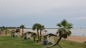 A beach area with small, simple huts and palm trees.