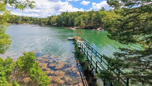 A wooden dock extending into a calm lake surrounded by dense forest.