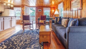 A wooden cabin interior with a living room, dining area, and kitchen.