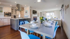 A modern kitchen with white cabinets, a dining area with blue chairs, and a ceiling fan. - Village Life, walk to the village of La Jolla (La Jolla)