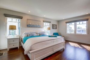 Une chambre à coucher avec un grand lit, des tables de chevet, une fenêtre donnant sur un beau paysage et une étagère murale décorative.