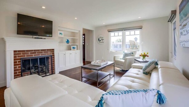 A modern living room with a fireplace, white sofas, a flat-screen TV, and a large window. - Village Life, walk to the village of La Jolla (La Jolla)