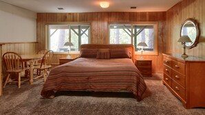 A bedroom with a wooden paneled wall, a bed with striped bedding, a dresser, a chair, and two windows with curtains. - (99) Yosemite Mountain Lodge at The Redwoods In Yosemite (Wawona)