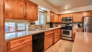 A kitchen with wooden cabinets, stainless steel appliances, a dishwasher, and a window providing natural light. - (99) Yosemite Mountain Lodge at The Redwoods In Yosemite (Wawona)