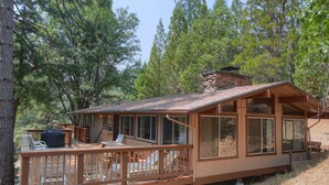 A cabin with a deck, outdoor seating, and large windows. - (99) Yosemite Mountain Lodge at The Redwoods In Yosemite (Wawona)