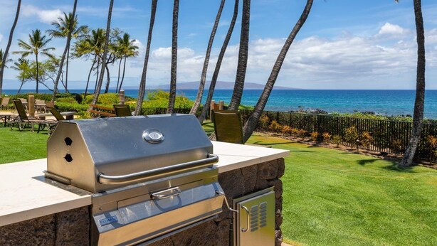A grill with a stone base, a view of the ocean, and palm trees. - Totally renovated, closest to the beach! (Kihei)