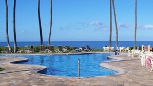 A pool area with lounge chairs and palm trees, overlooking the ocean. - Totally renovated, closest to the beach! (Kihei)