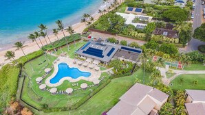 An aerial view of a coastal property with a swimming pool, palm trees, and a road. - Totally renovated, closest to the beach! (Kihei)