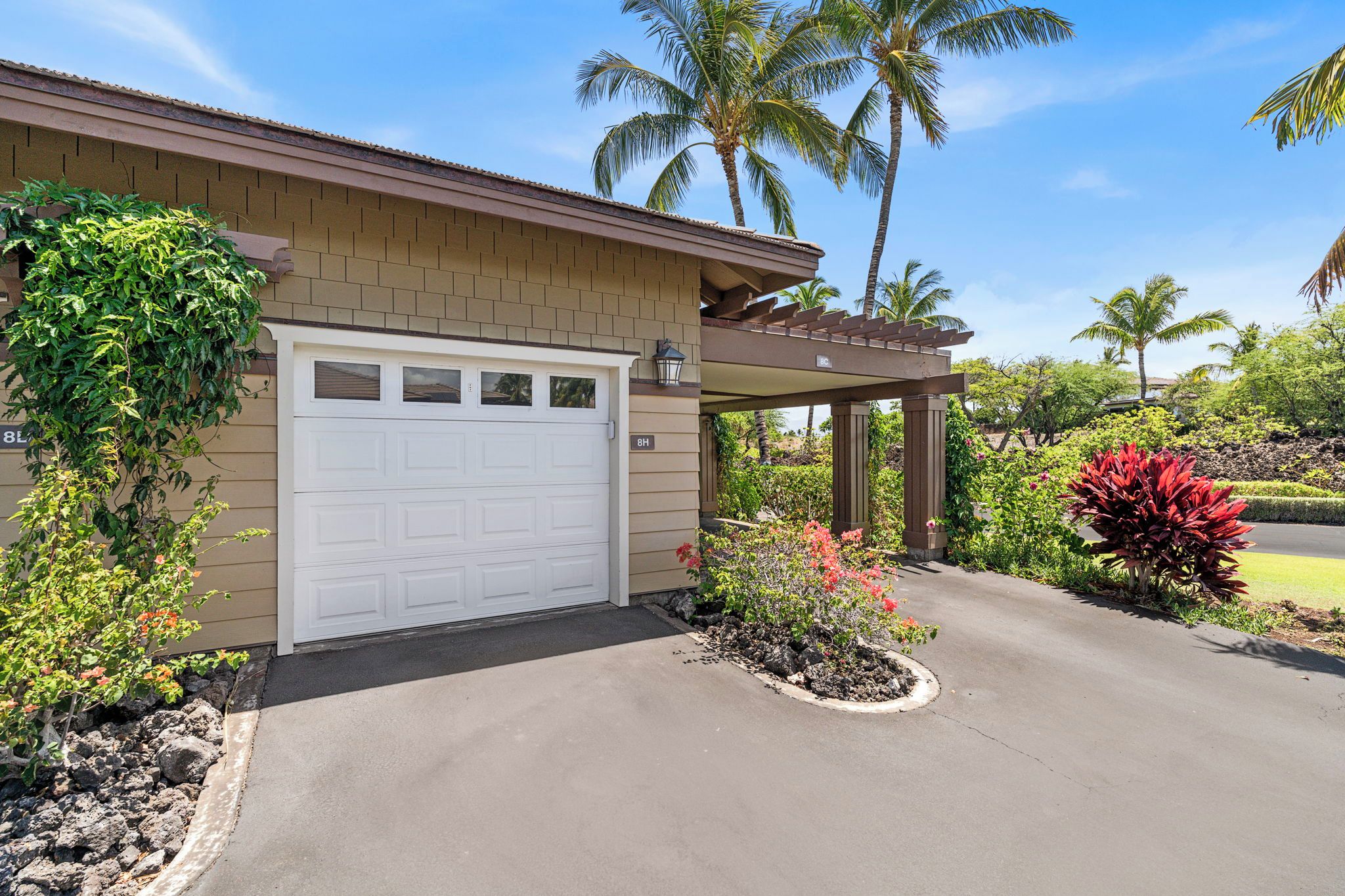 A residential building with a garage, a covered porch, and a landscaped driveway.