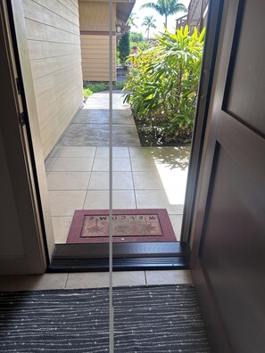 A doorway leading to a tiled patio with a welcome mat.