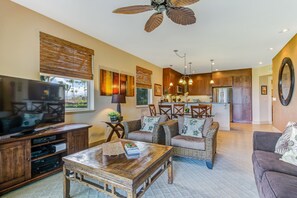 A spacious living room with a large flat-screen TV, a wooden coffee table, and a comfortable sofa.