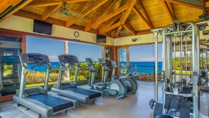 Academia com esteiras, elípticos e aparelhos de musculação, com vista panorâmica.