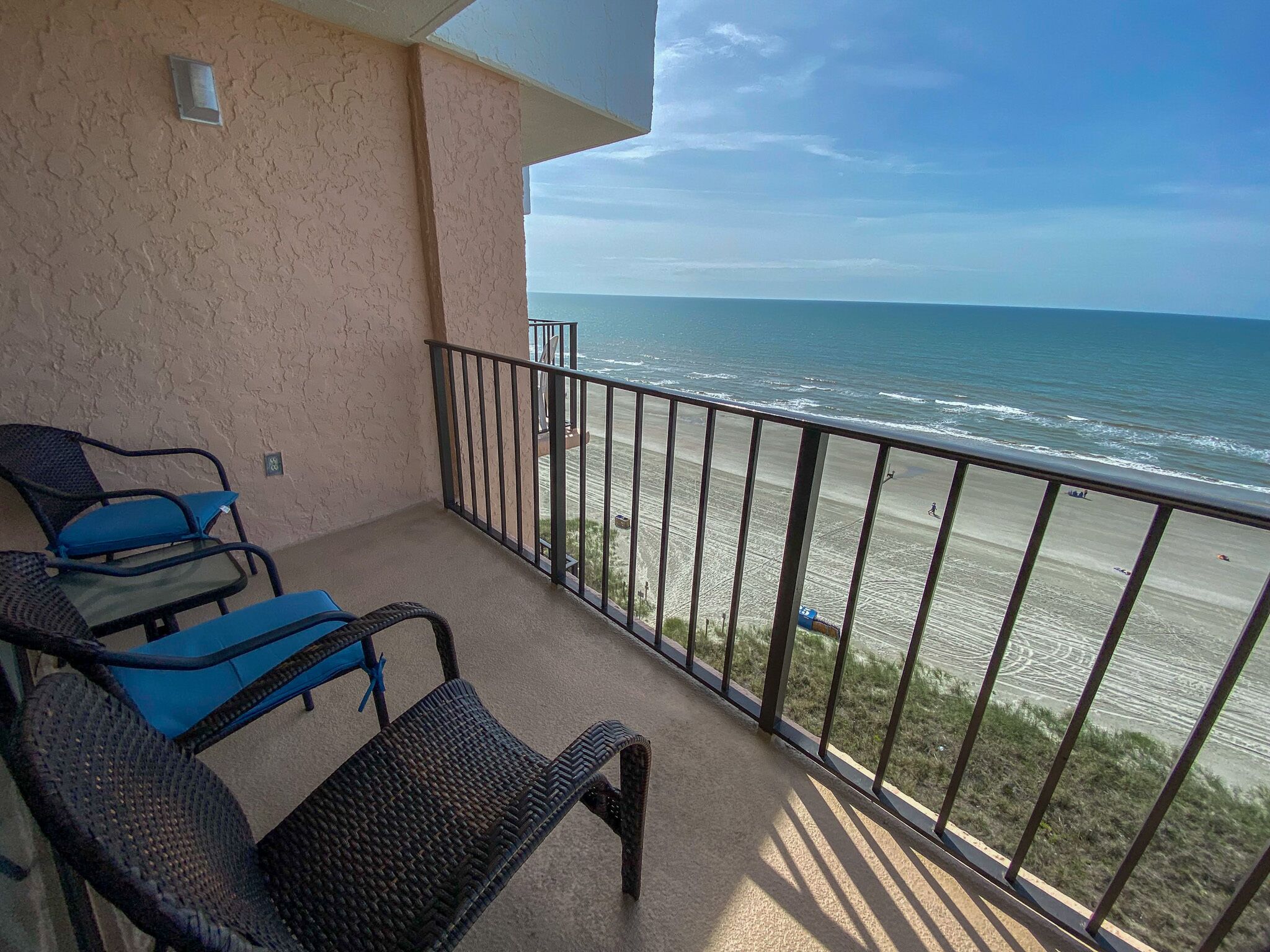A balcony with wicker furniture and a view of the beach.
