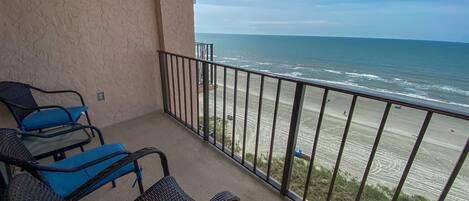 A balcony with wicker furniture and a view of the beach.