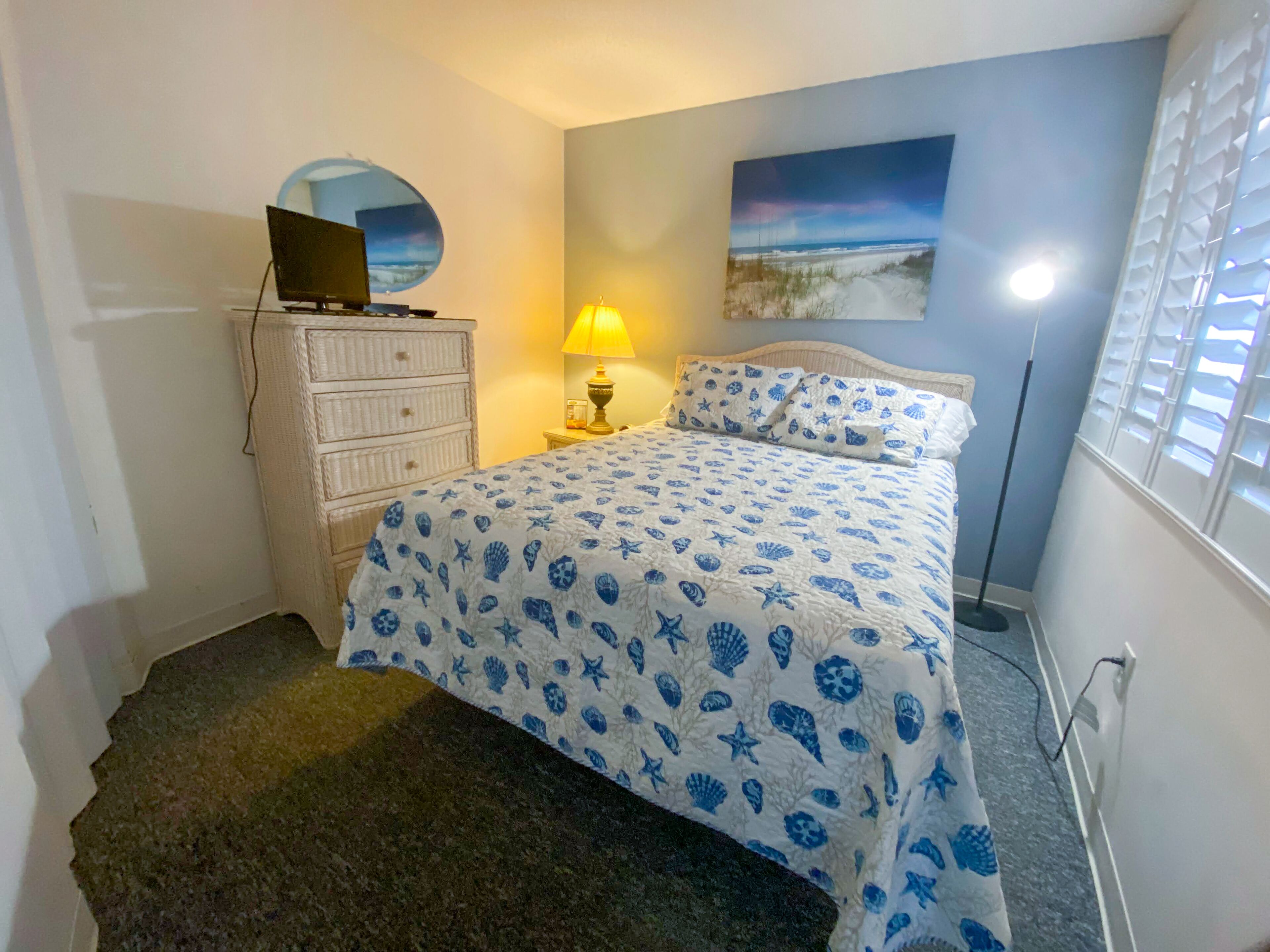A bedroom with a bed, dresser, lamp, and a painting on the wall.