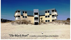 Um condomínio de férias chamado "The Black Pearl" em A Place at the Beach IV, apresentando uma estrutura em vários andares com varandas e localização à beira-mar.