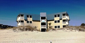 Un appartement de vacances appelé « La Perle noire », situé dans la résidence « A Place at the Beach IV », qui se distingue par son architecture à plusieurs étages, ses balcons et son emplacement en bord de mer.